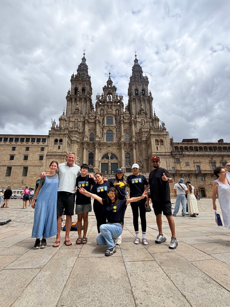 Group of people posing in front of ornate cathedral with twin spires in town plaza